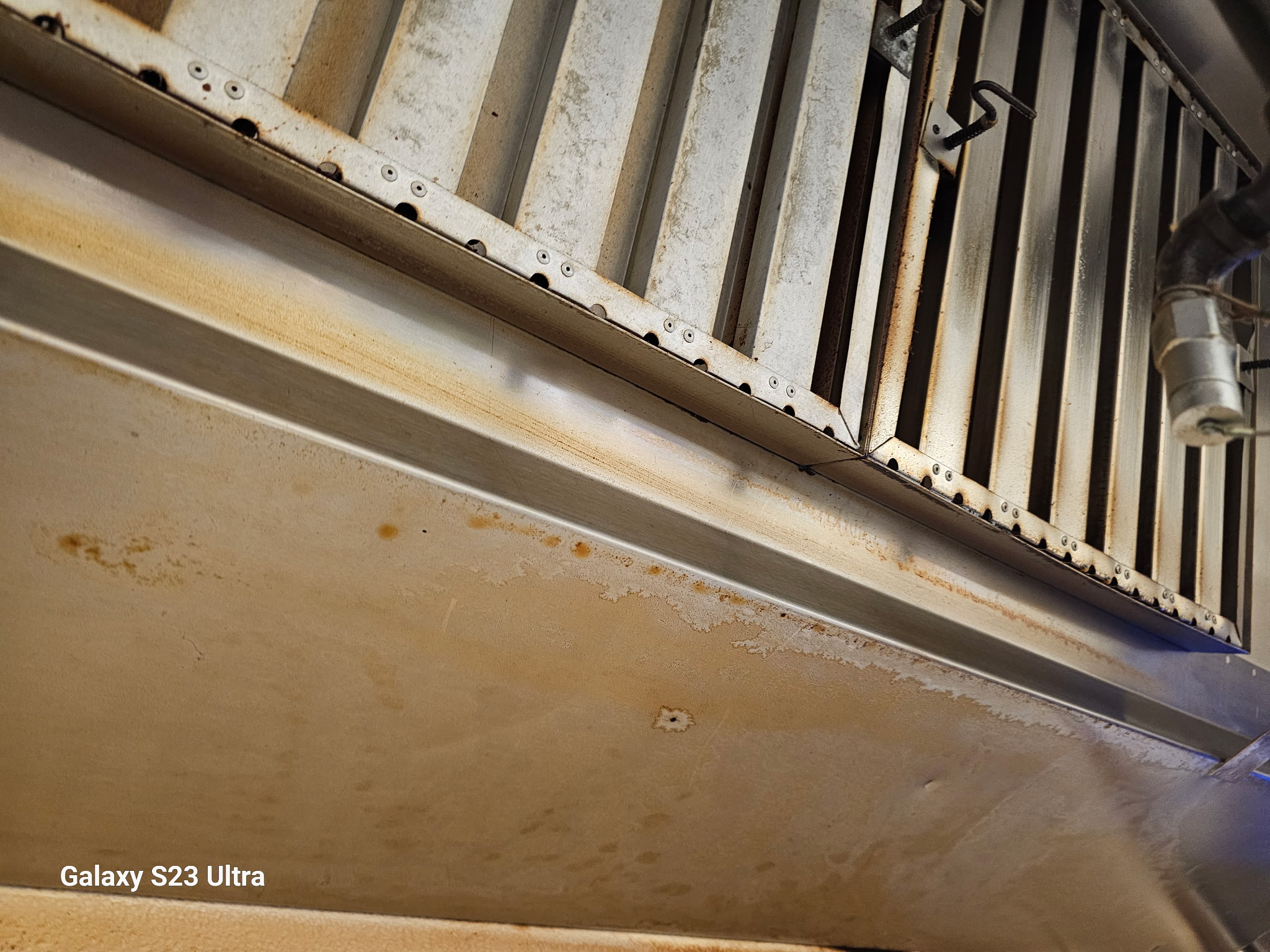 Grease buildup on a commercial kitchen exhaust hood before cleaning